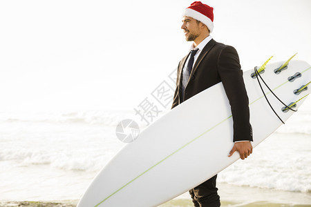 男生身戴圣诞老人帽子并持有冲浪板的商业家运动爱好图片