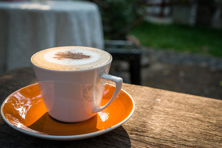 卡布奇诺咖啡白杯加在花园的木桌上香气子艺术图片