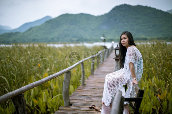 年轻的自然松弛坐在码头上的女人看着日落的美丽图片