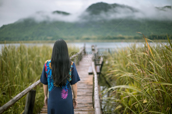 木制的旅行女孩坐在码头上的女人看着日落的美丽图片