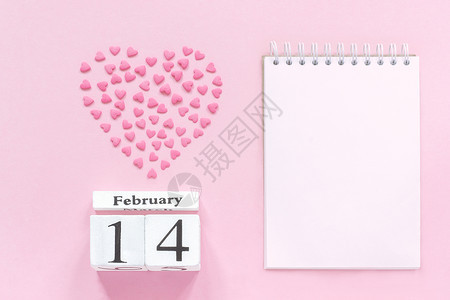 调度器躺着白色的木方日历2月14日和粉红色糖果的心洒在形上空的打开记事本用于粉红色背景上的文本粉红色背景概念Valentiner图片