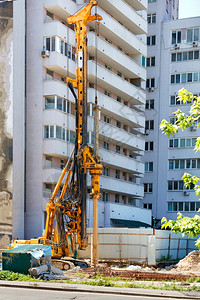 无聊的一种液压钻机在建筑工地进行钻井作业与堆叠的无聊一起工作垂直图象钻井机在施工地驾驶水泥堆金属图片