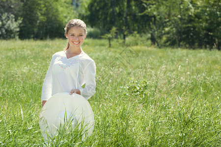 春天快乐的年轻女子站在绿色夏月草原上戴白帽子的少女服装白色图片