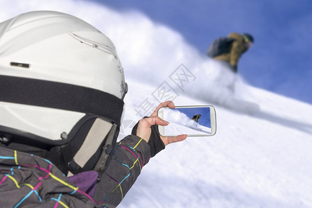 一名年轻女孩用手机拍下山上滑雪搭便车驾驶员的照片景观跳线年轻的图片