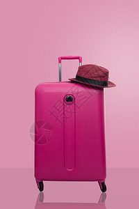 手推车休息粉色提箱上面戴贴粉红背景旅行概念最低风格夏天图片