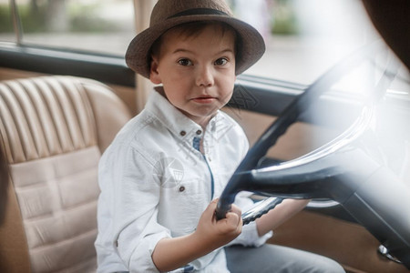 穿着古老衣服的白人小男孩坐在一辆旧车里运输皮革游客图片