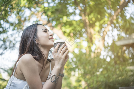 清晨在公园喝咖啡时年轻美丽的女子感到快乐和有权势同时在公园喝咖啡户外女士技术图片