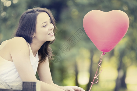 阳光情人节快乐微笑的年轻女站在红形心气球外出门前快乐的图片