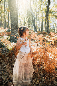 小caucasians幼女孩站在森林里与植物一起玩耍幸福观察树叶图片