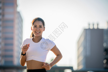 早晨成人活力亚洲青年健身运动女在城市公路上奔跑和微笑图片