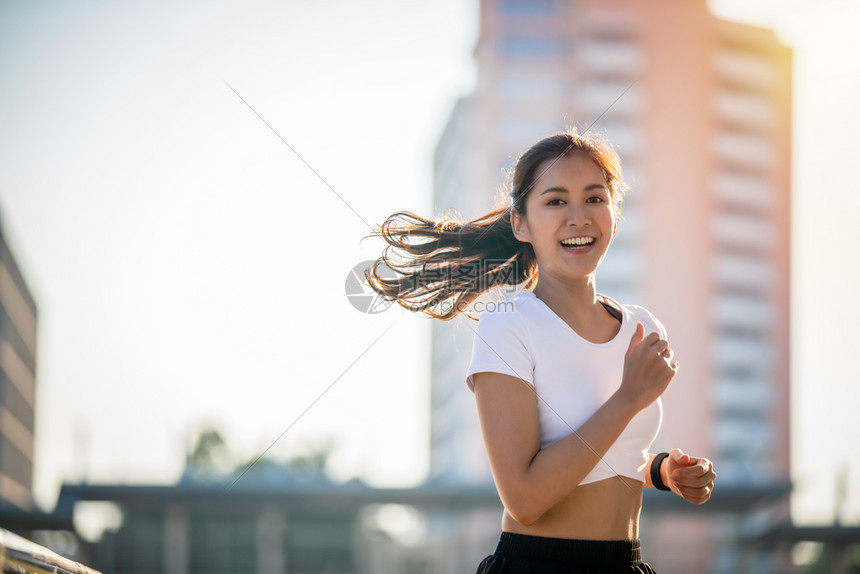 早晨马拉松亚洲青年健身运动女在城市公路上奔跑和微笑人图片