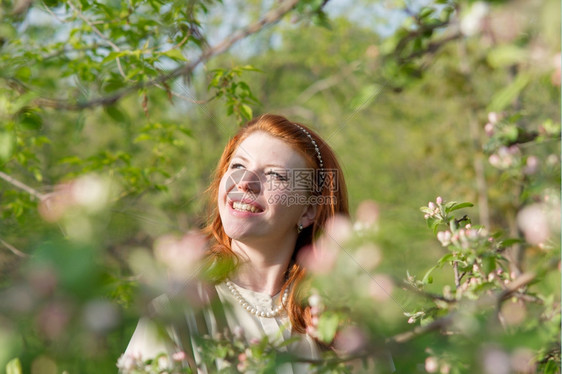 微笑花朵春天可爱的红头发女孩走进苹果园图片