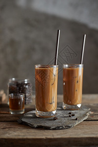 牛奶黑色的凉爽冰咖啡在木制桌上的高玻璃杯中图片