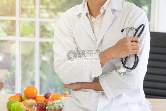 医生或营养师坐在办公桌上诊所里拿着水果和维生素瓶健康饮食营养品作为健康处方的概念水果是药新鲜的重量控制图片