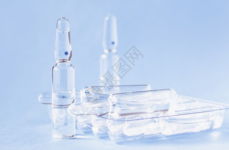蓝色背景桌上的玻璃疫苗瓶图片