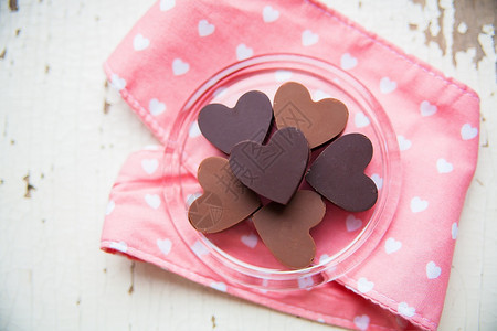 黑暗的营养装饰巧克力糖果以心脏的形状在盘子上与粉红色毛巾巧克力糖粉红色毛巾和图片