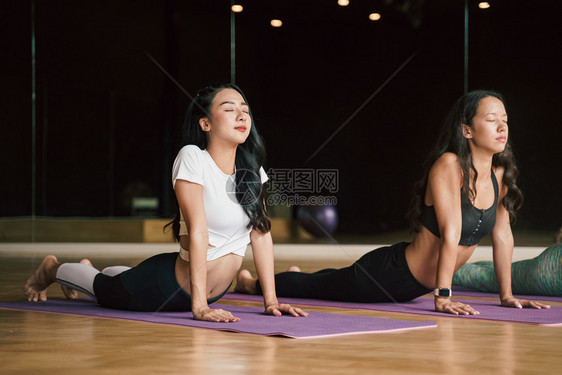 重量体育场瑜伽垫子上穿眼镜蛇的青年团体放松和默思概念在体育场瑜伽垫上摆姿势脸说谎图片