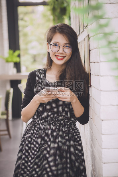 泰国亚洲人带着智能手机面对幸福的情感手握着智能机并微笑着快乐的容手表图片