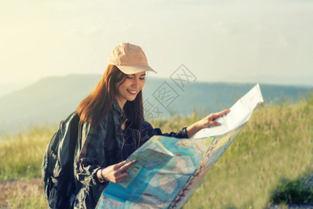 背着明亮包的女亚洲在背景山上观光旅行者背面的浏览视电话手旅游图片