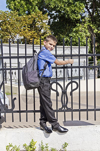 男人可爱的孩背着书包挂在栅栏上男孩背着书包挂在栅栏上十四肖像图片
