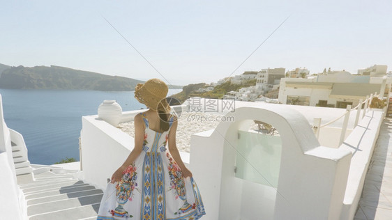 在圣桑托里尼Oia村与欧洲Santorini夏季目的地中海在楼梯上行走的女游客背面欧洲的城市帽子图片