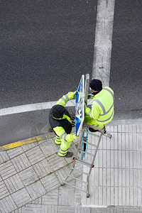 在街上人行道安装新路标的工人公共维护概念机器街道职业图片