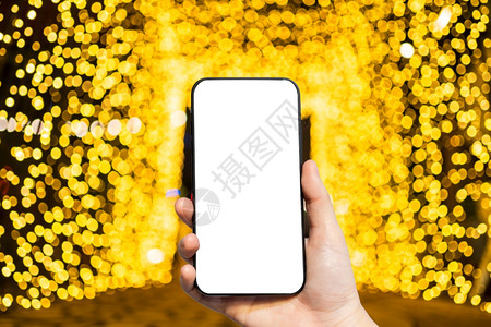 聪明的喜庆利用黄色彩光照智能手机模糊图像和黄色彩亮光简要循环圣诞和新年树背景装饰的Bokehbookh新的图片