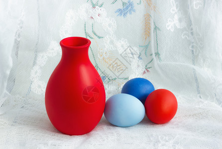 蕾丝营养树三个漆成红色和蓝的复活节鸡蛋一个陶瓷喷鸦在白年换花板桌布上重点选放在前方三度复活彩蛋和A片图片
