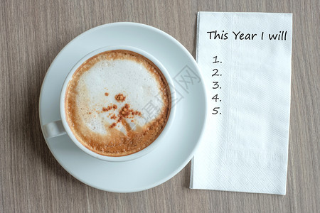 喝快乐的将要今年我用热卡布奇诺咖啡杯在新年开始解决方案战略和使命概念的清晨桌边背景上讲话Name图片