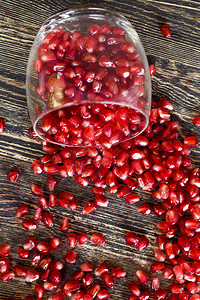 仍然活着的玻璃杯和红石榴颗粒分散在桌子周围健康的果实红石榴甜点大约异国情调图片