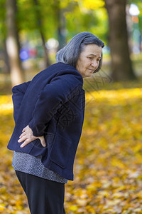 秋天公园户外背部疼痛的老年妇女图片