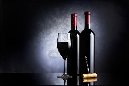 抽象的酒杯和两瓶黑背景的葡萄酒饮料赤霞珠图片