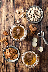 两杯新鲜啤酒和咸点心放在棕色木制桌子上最美景泡沫食物棕色的图片