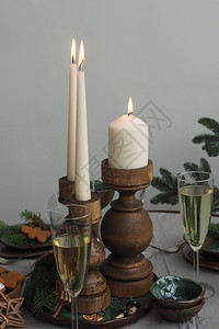 木烛台桌子上三根烧着的蜡烛两杯香槟树枝绿褐陶瓷杯云杉色一种图片