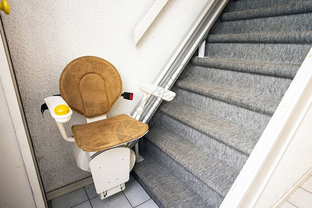 步楼梯上的自动升降机将老年人和残疾在房屋中上下现代的内部背景图片