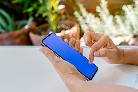 空的用人手触摸智能电话蓝色屏幕用于使技术和社交媒体概念的人类触碰手法数字的在线图片