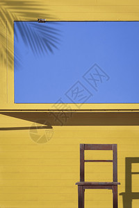 建筑学商业框架在垂直状的黄色和蓝咖啡街亭前木椅表面的阳光和阴影在垂直架上图片