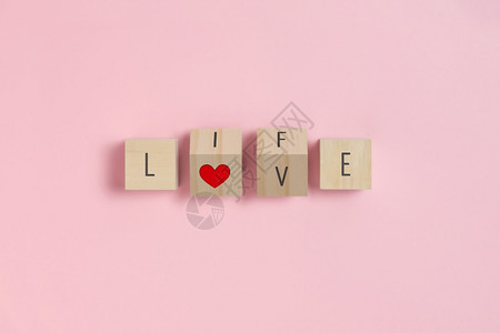 婚礼木头爱生命文字和红心在Wooden立方体上粉红色背景的情人节概念作品图片