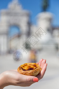 在葡萄牙里斯本的背景点上葡萄牙传统妇女手中的Pasteisdenataspathesnata女传统的甜点图片