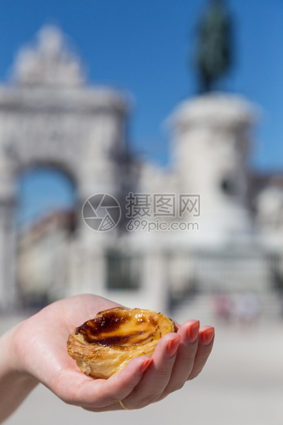 城市在葡萄牙里斯本的背景点上葡萄牙传统妇女手中的Pasteisdenataspathesnata传统的食物图片