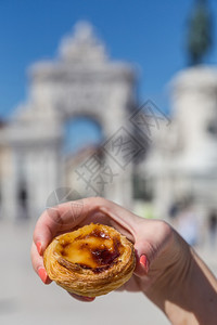 粉彩午餐在葡萄牙里斯本的背景点上葡萄牙传统妇女手中的Pasteisdenataspathesnata美味的图片