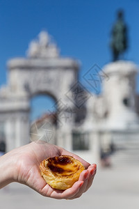 传统的在葡萄牙里斯本的背景点上葡萄牙传统妇女手中的Pasteisdenataspathesnata旅游客图片