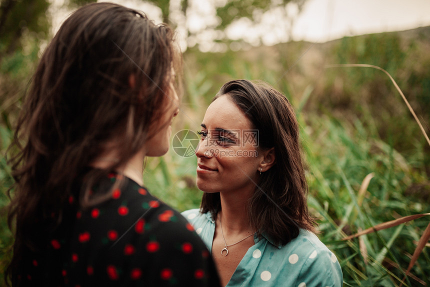 自然两个年轻的女者在田里微笑着穿衣服看对方拥抱随意的图片