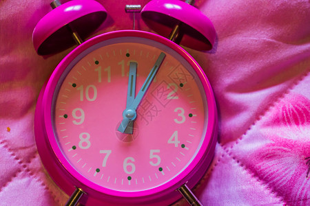 唤醒超过粉红背景色老旧闹钟的大型关闭睡眠图片