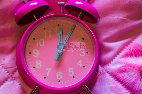 唤醒超过粉红背景色老旧闹钟的大型关闭睡眠图片