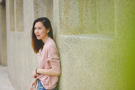 时尚粉色的年轻身穿粉红衬衫靠在建筑物墙上的女人图片