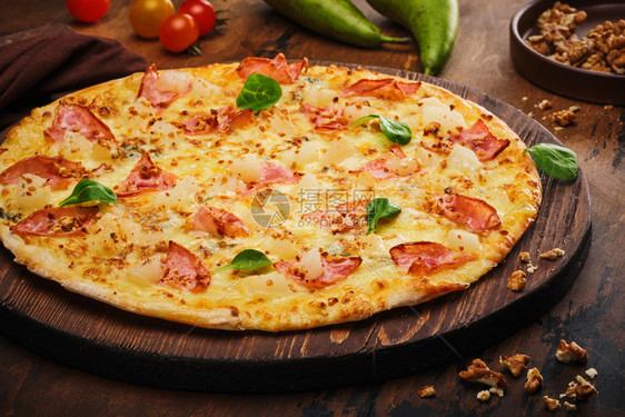 快速地烘烤的可口新鲜准备美味披萨还有梨子坚果和培根在木板上图片