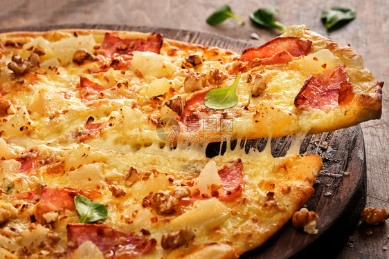 意大利新鲜准备的美味披萨还有梨子坚果和培根在木板上自制热的图片