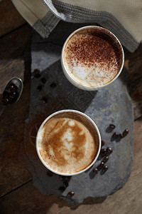 新鲜的卡布奇诺木制桌上的热咖啡杯和豆拿铁图片