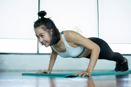 锻炼参加健身培训的妇女健身穿戴高训练长子年轻女在健身时做俯卧撑在健身时做俯卧跳的肌肉女运动推图片
